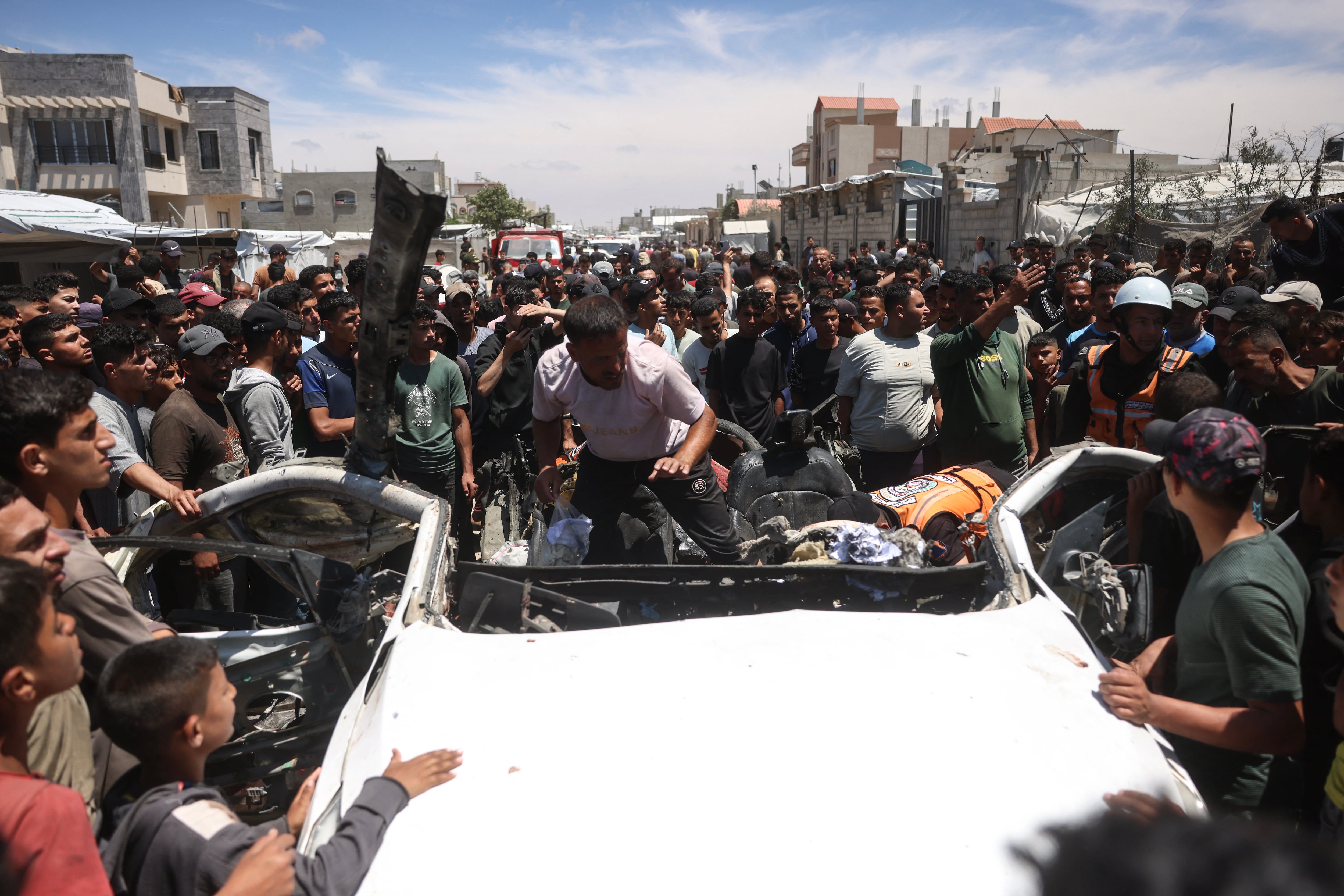 Defensa civil palestina inspecciona los restos de un vehículo alcanzado por un ataque israelí