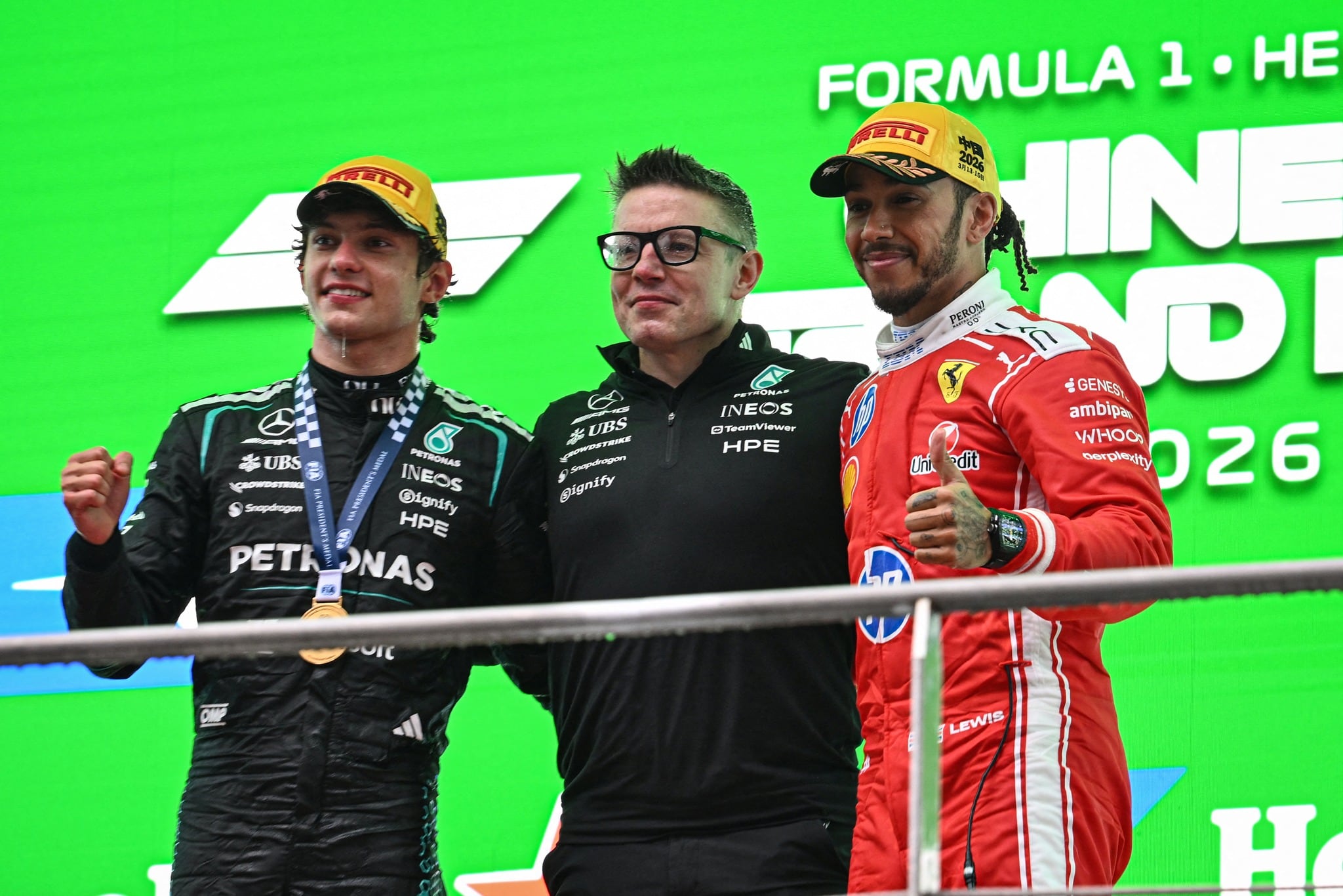 El piloto italiano de Mercedes, Kimi Antonelli (izquierda), ganador de la carrera, y el piloto británico de Ferrari, Lewis Hamilton (derecha), que quedó en tercer lugar, celebran en el podio con el ingeniero de carrera de Mercedes, Peter Bonnington, tras el Gran Premio de China de Fórmula 1 en el Circuito Internacional de Shanghái, el 15 de marzo de 2026. (Foto de Jade GAO / AFP vía Getty Images)