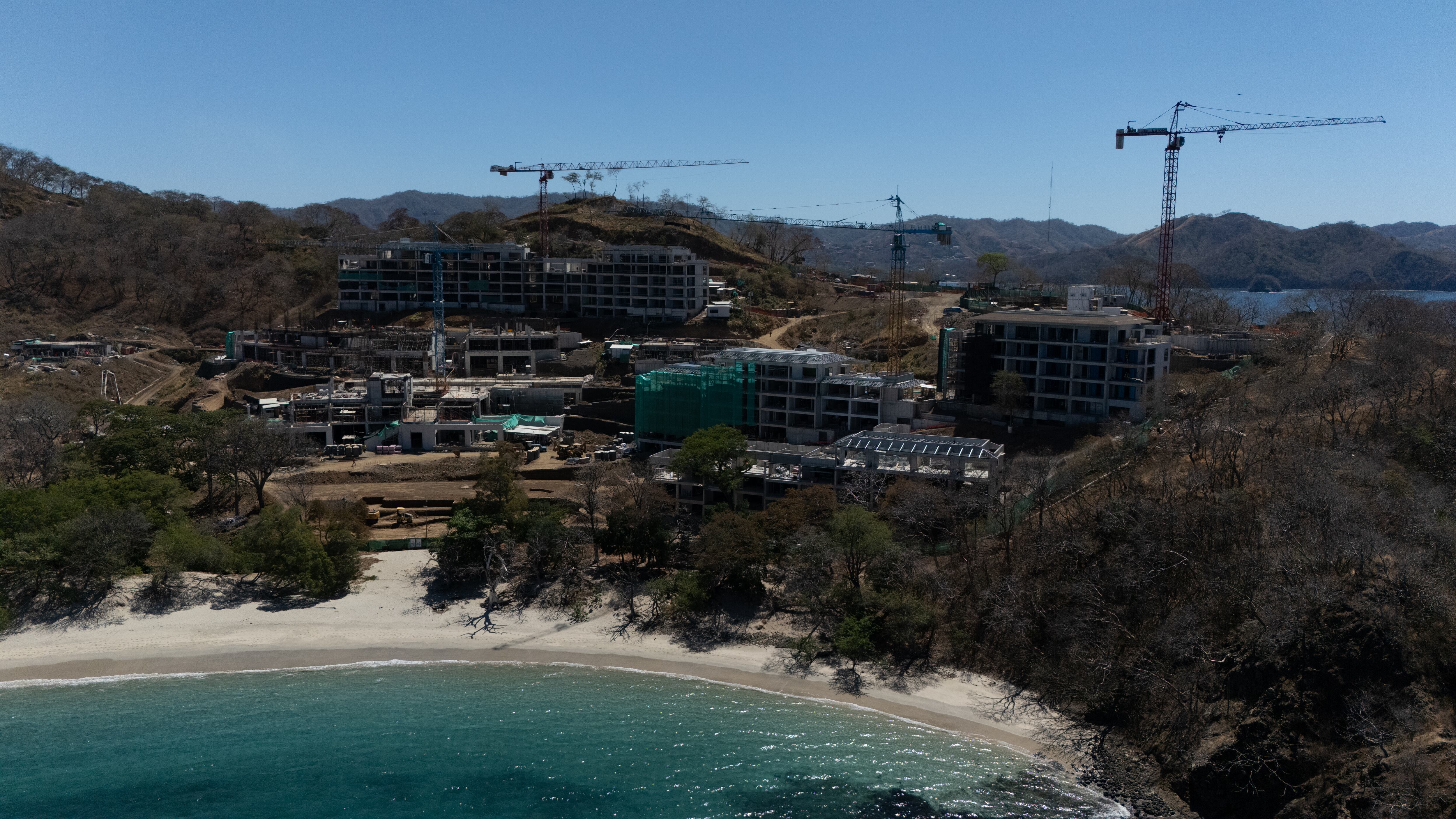 Vista aérea de la construcción del Hotel Waldorf Astoria Punta Cacique en Guanacaste, con grúas y estructuras rodeadas por vegetación y playa.