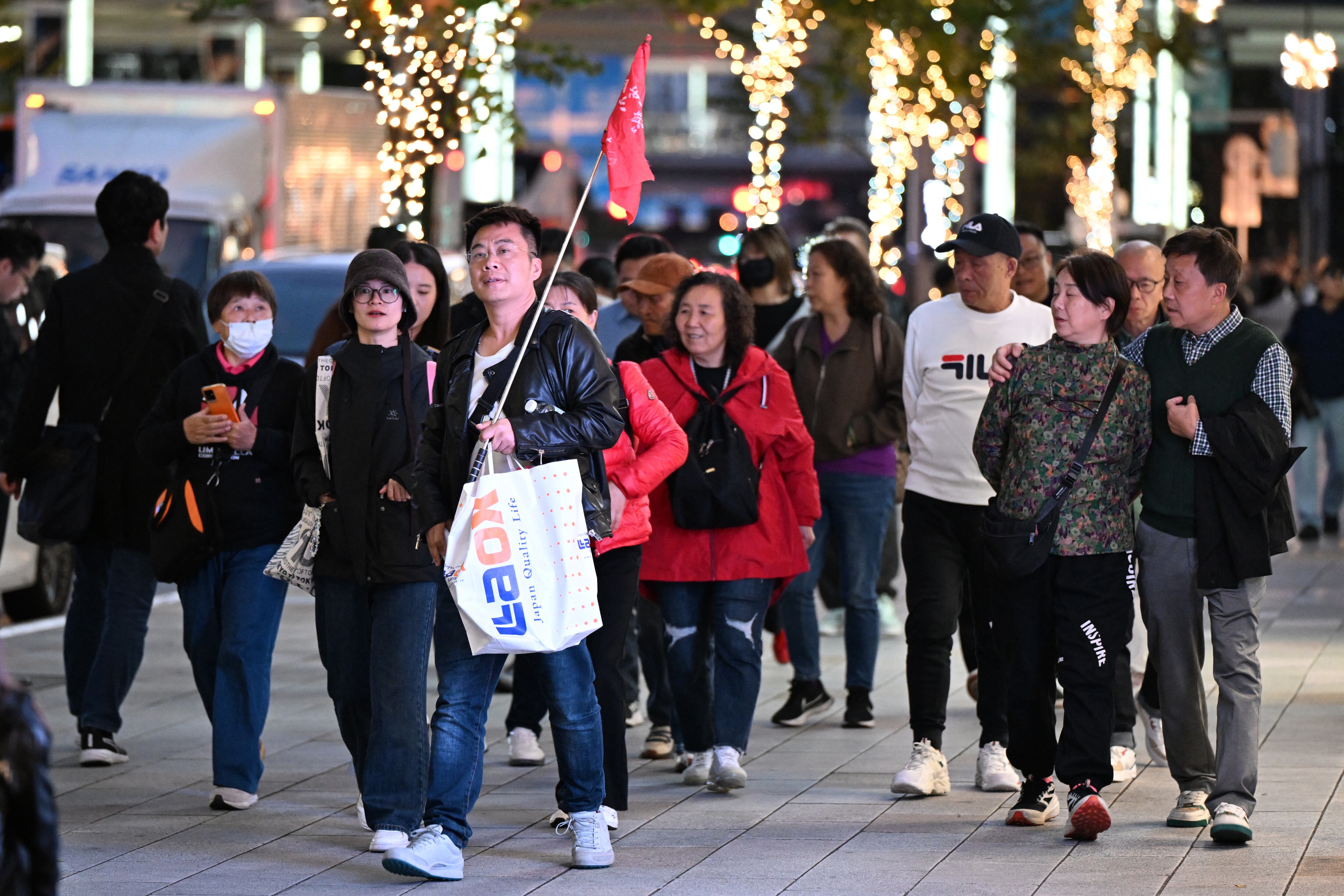 Un grupo de turistas chinos pasea por el distrito comercial de Ginza en Tokio este 17 de noviembre. Las acciones de turismo y comercio minorista japonesas se desplomaron ese día después de que China advirtiera a sus ciudadanos que evitaran la zona turística, en medio de una disputa por las declaraciones de la primera ministra Sanae Takaichi sobre Taiwán. Fotografía: