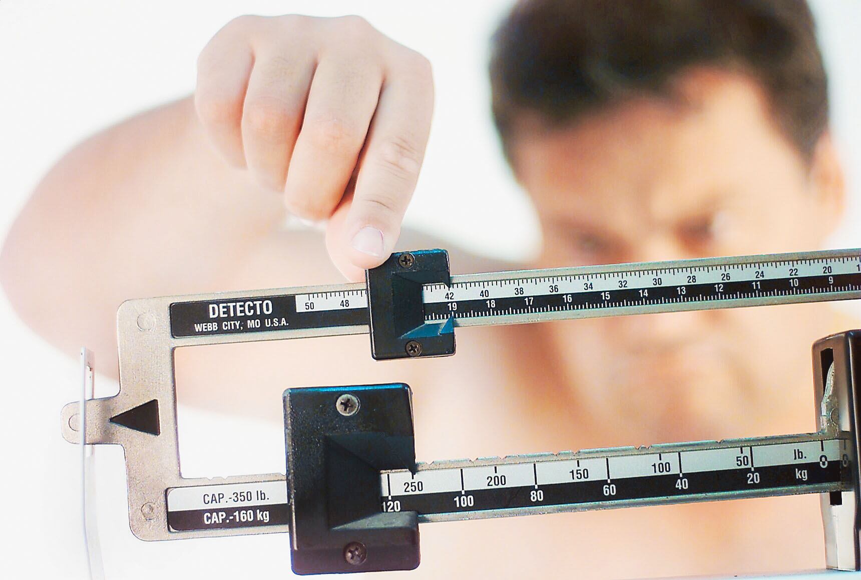 Un hombre mueve el mecanismo de una pesa para ver cúántos kilogramos pesa