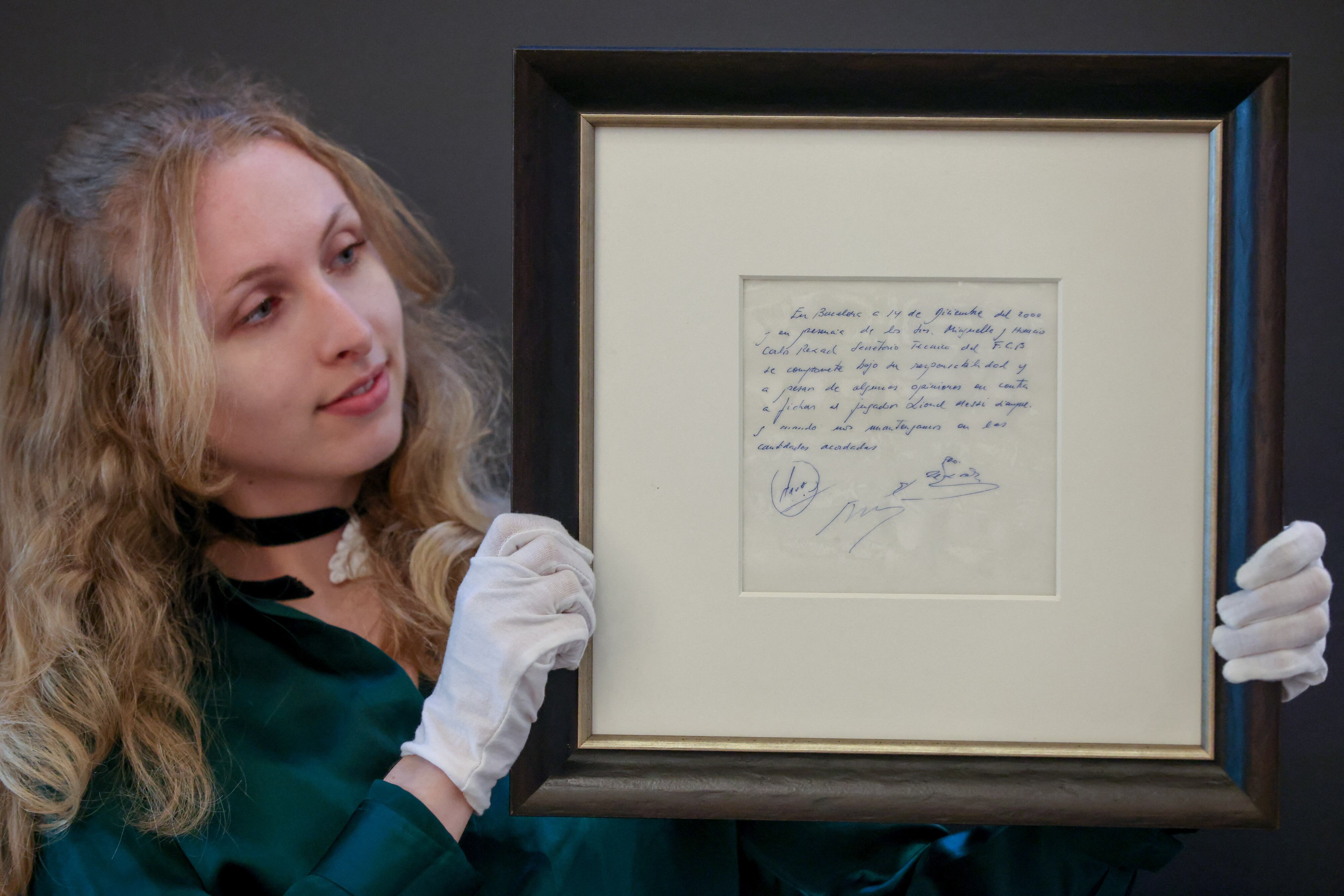 Una funcionaria de la Galería Bonhams, en Londres, muestras la famosa servilleta del contrato de Lionel Messi, en mayo de 2024, antes de ser subastada.