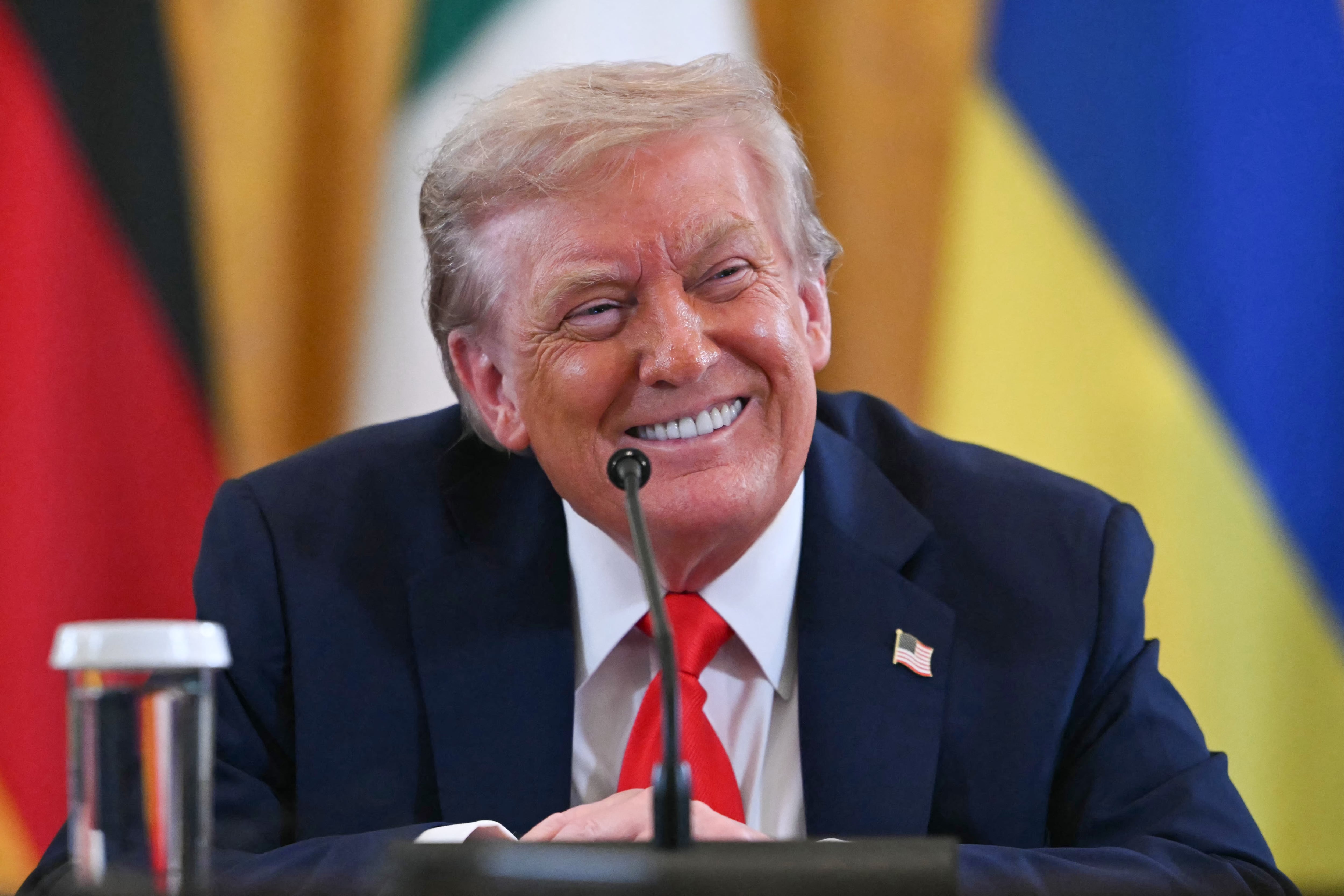 US President Donald Trump smiles during a meeting with Ukrainian President Volodymyr Zelensky and European leaders in the East Room of the White House in Washington, DC, on August 18, 2025. European leaders join Ukrainian President Volodymyr Zelensky in talks with US President Donald Trump on August 18, as they try to find a way to end Russia's offensive. The leaders heading to Washington on Monday to appear alongside Zelensky call themselves the "coalition of the willing." (Photo by ANDREW CABALLERO-REYNOLDS / AFP)