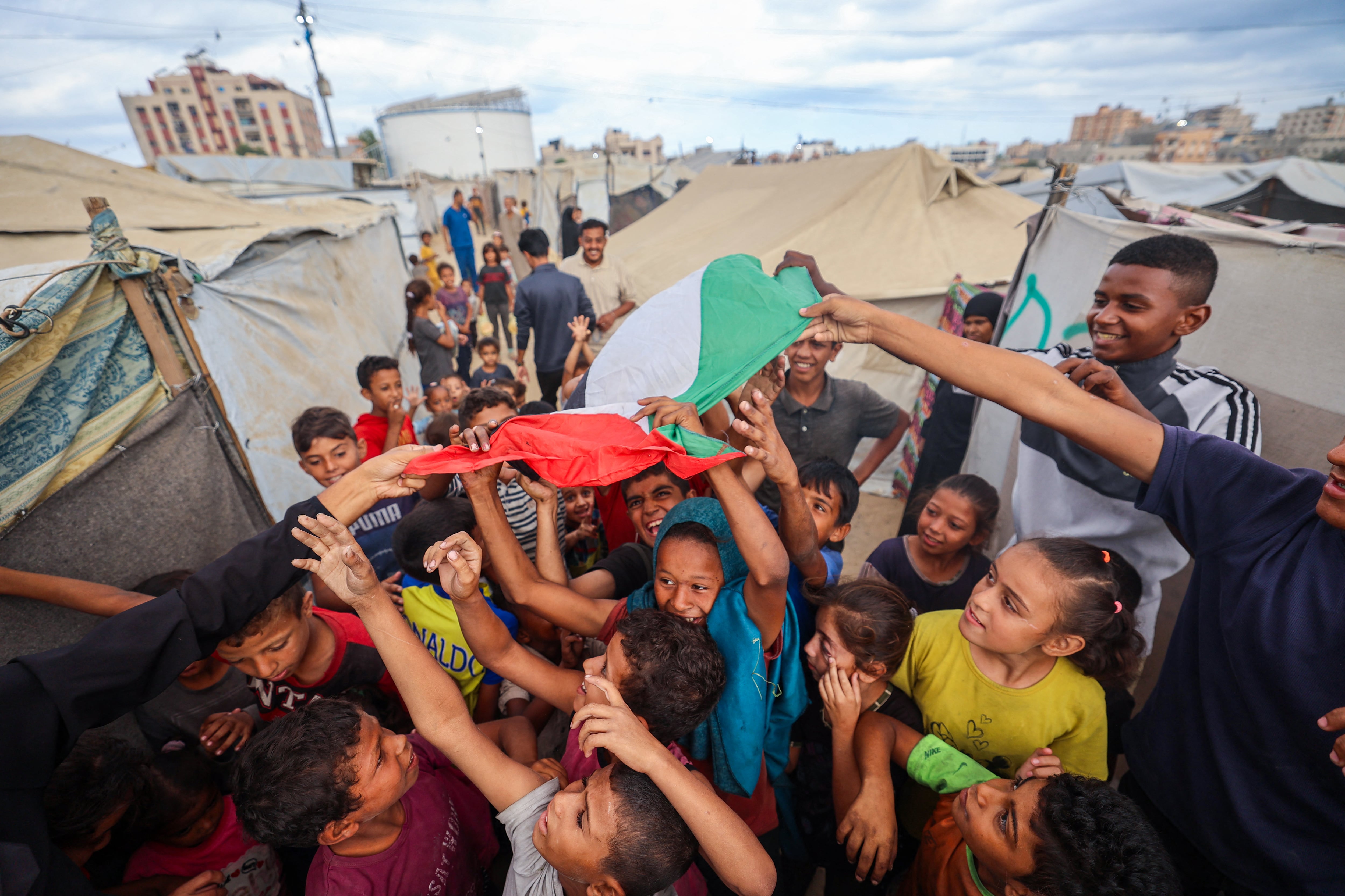 Niños palestinos celebran en un campamento para desplazados en Nuseirat, en el centro de la Franja de Gaza, este 9 de octubre, tras la noticia de un nuevo acuerdo de alto el fuego en Gaza. Fotografía: