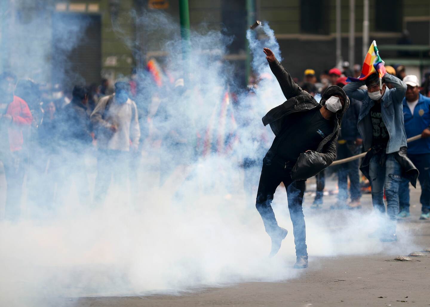 A backer of former President Evo Morales returns a tear gas canister at the police during clashes in La Paz, Bolivia, Wednesday, Nov. 13, 2019. Bolivia's new interim president Jeanine Anez faces the challenge of stabilizing the nation and organizing national elections within three months at a time of political disputes that pushed Morales to fly off to self-exile in Mexico after 14 years in power. (AP Photo/Natacha Pisarenko)