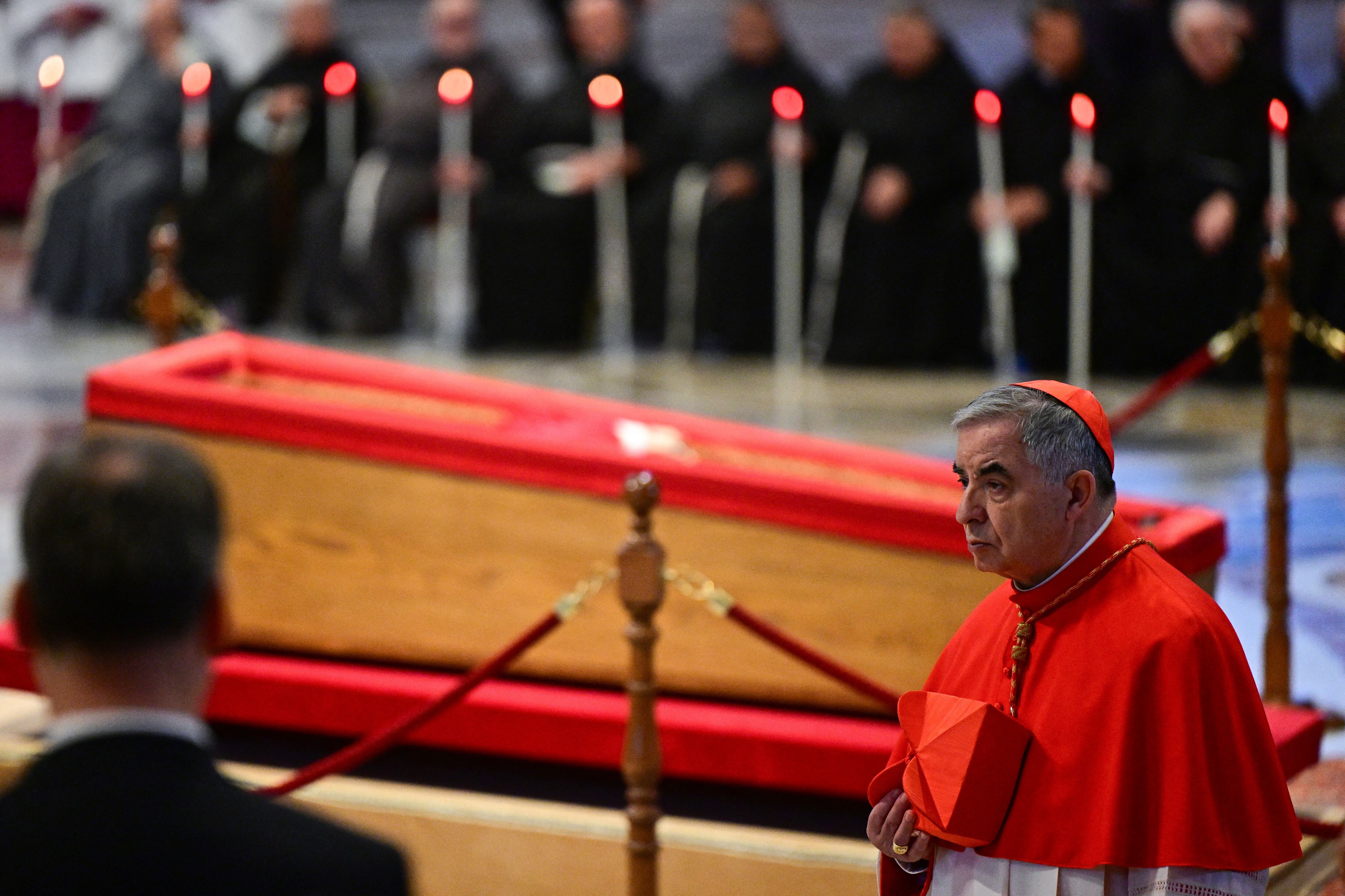 Giovanni Angelo Becciu walks next to the coffin after paying his respects during a ceremony inside St Peter's Basilica following the procession of the late Pope's coffin from the chapel of Santa Marta to St Peter's Basilica, in the Vatican on April 23, 2025. The Pope died of a stroke, the Vatican announced hours after the death on April 21, 2025, of the 88-year-old reformer who inspired devotion but riled traditionalists during 12 years leading the Catholic Church. (Photo by Tiziana FABI / AFP)
