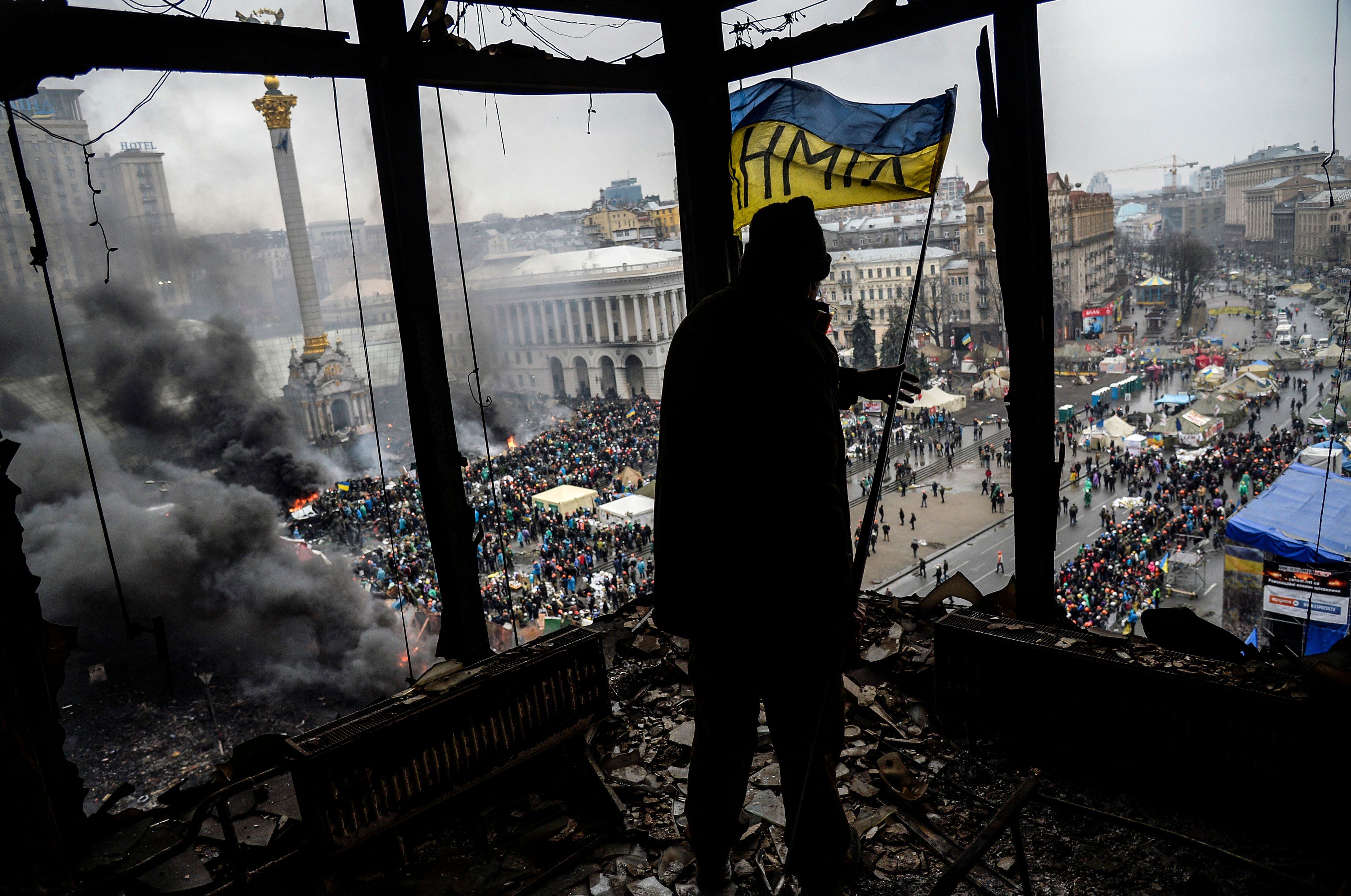 Un manifestante sostiene una bandera nacional ucraniana desde un edificio quemado durante un enfrentamiento contra la policía el 20 de febrero de 2014 en Kiev. Hace diez años, las manifestaciones ucranianas conocidas como el levantamiento de Maidan o Euromaidan llevaron a la caída del régimen del ex presidente Viktor Ianoukovitch en febrero de 2014, después de tres meses de protestas en Kiev y en su Plaza de la Independencia.