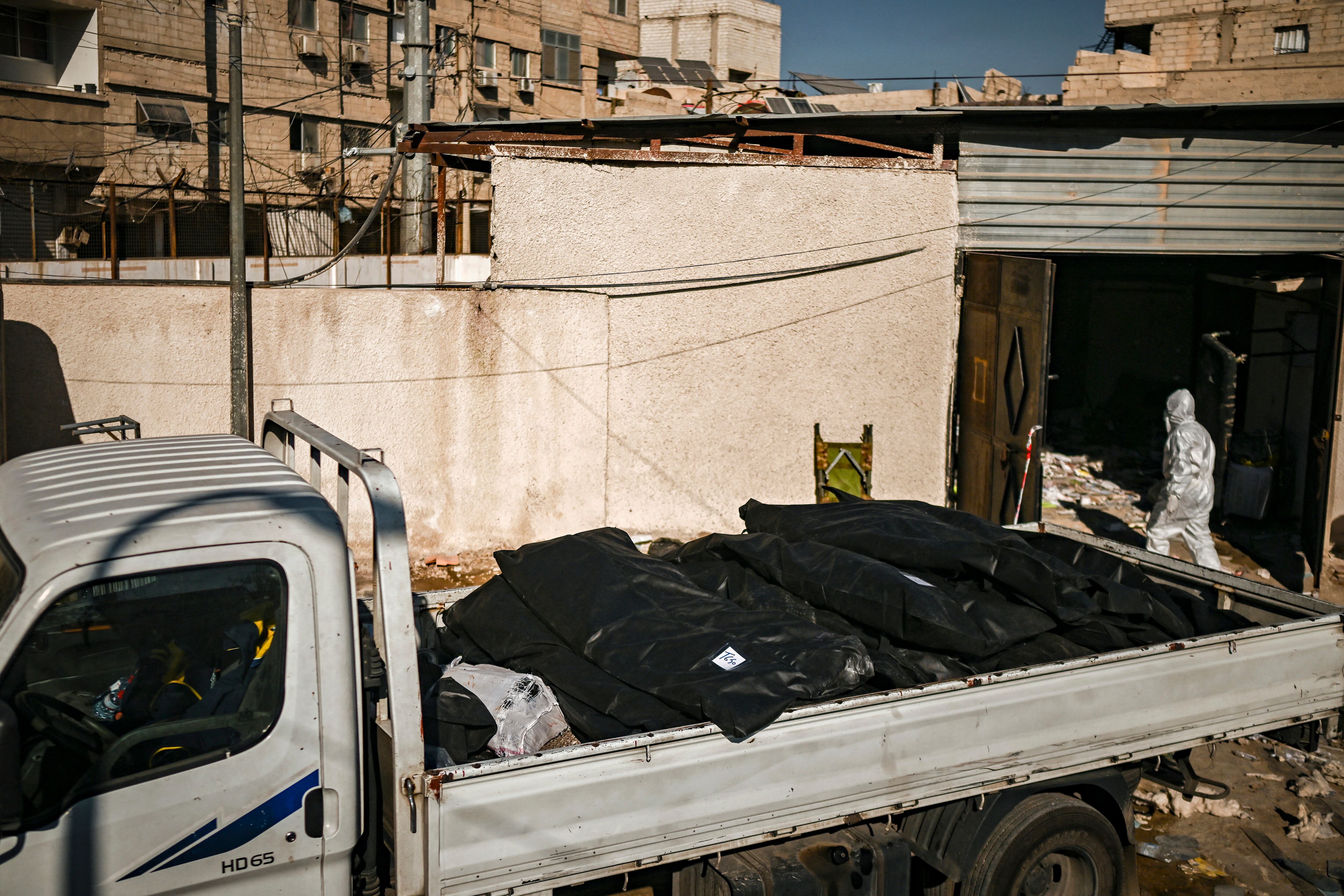 Miembros del servicio de defensa civil de los Cascos Blancos de Siria evacuan restos humanos en bolsas para cadáveres de un almacén en el distrito de Sayyida Zeinab, en el sur de Damasco.