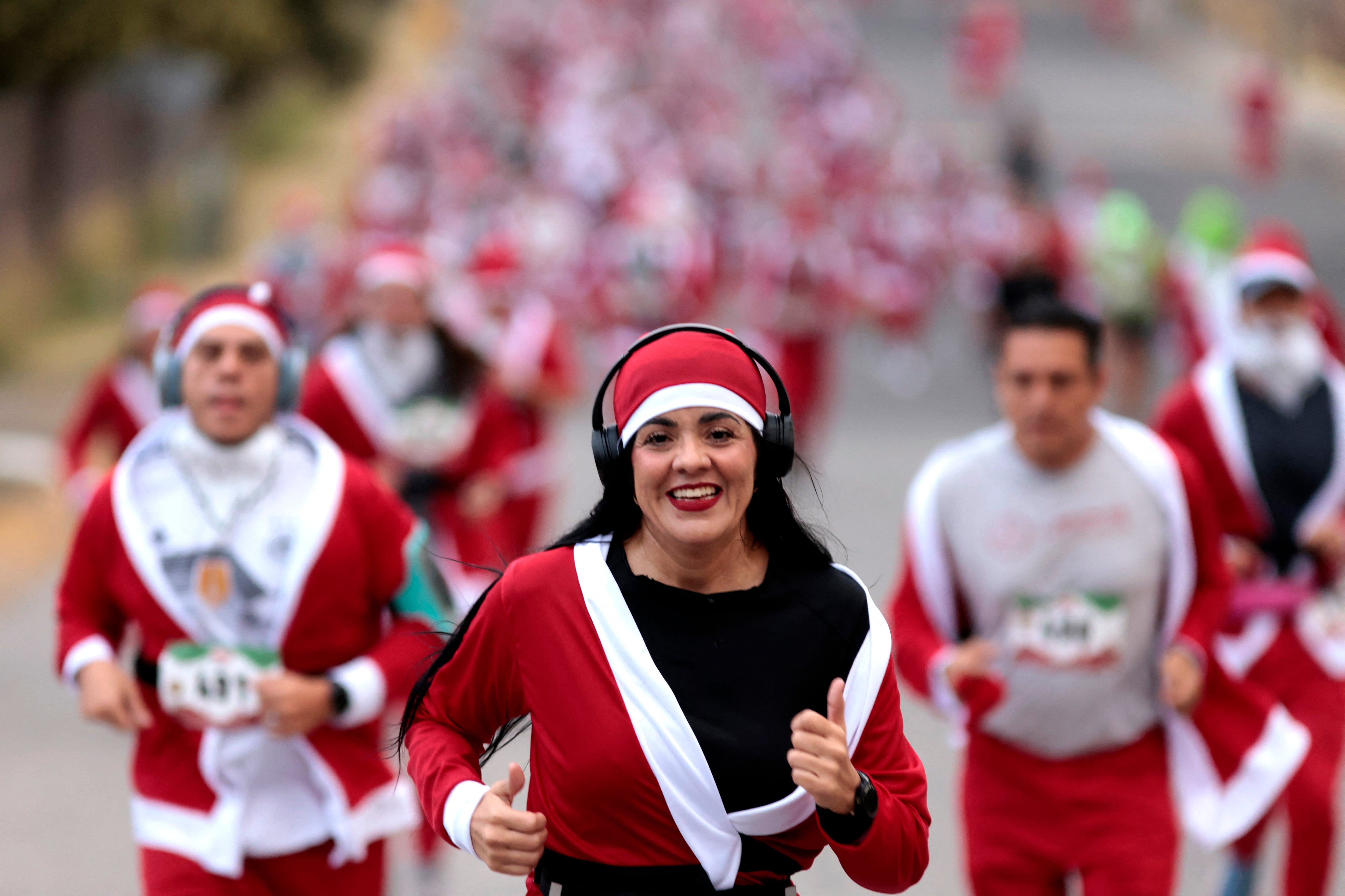 Mujer vestida como Santa Claus sonríe mientras corre en la multitud durante la carrera 'Run Santa Run' en Zapopan, México, el 8 de diciembre de 2024.