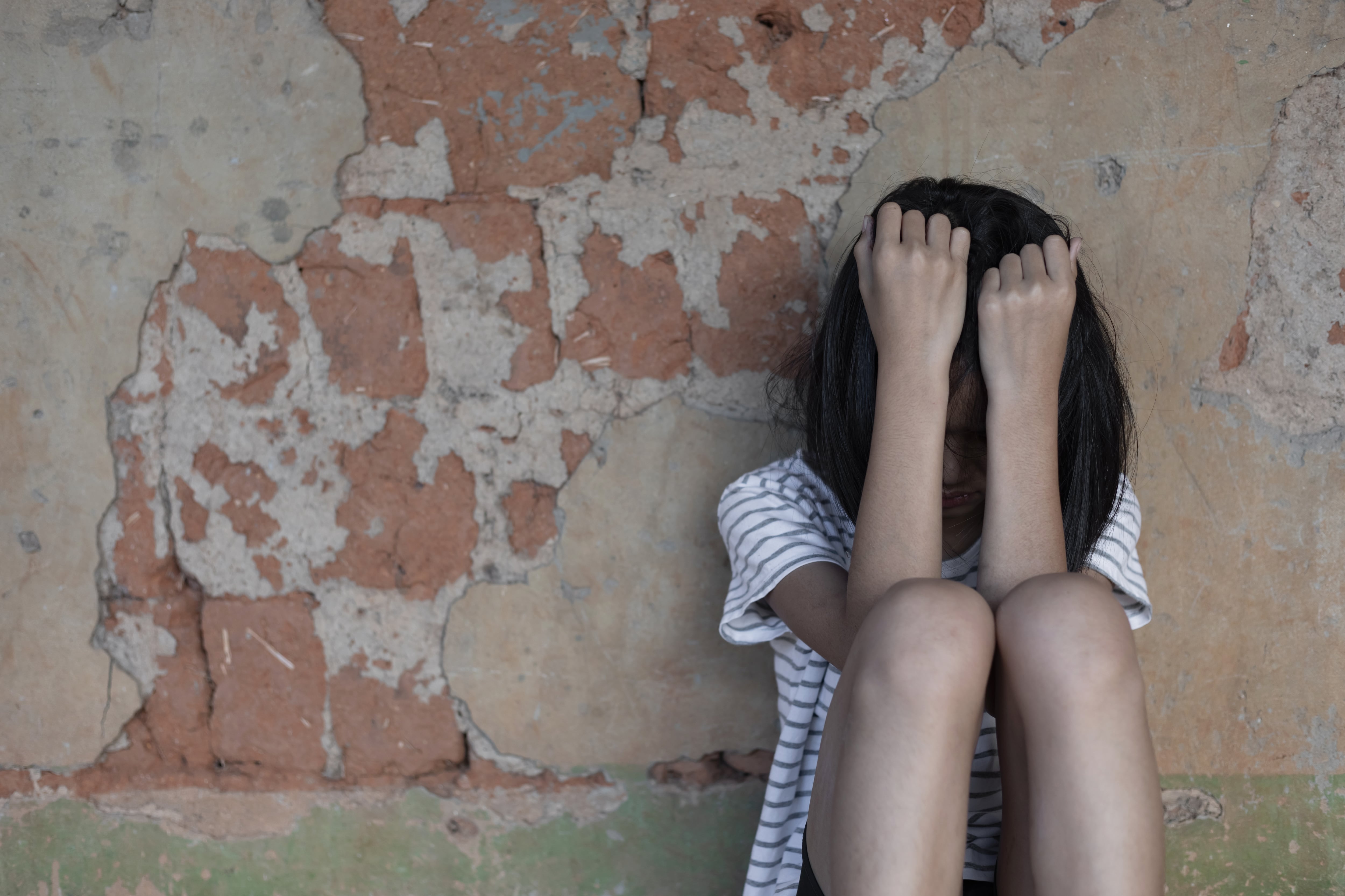 Menor en riesgo social, en vulnerabilidad. Niña sentada en el suelo cubriéndose la cara con los brazos, niñez, adolescencia, PANI