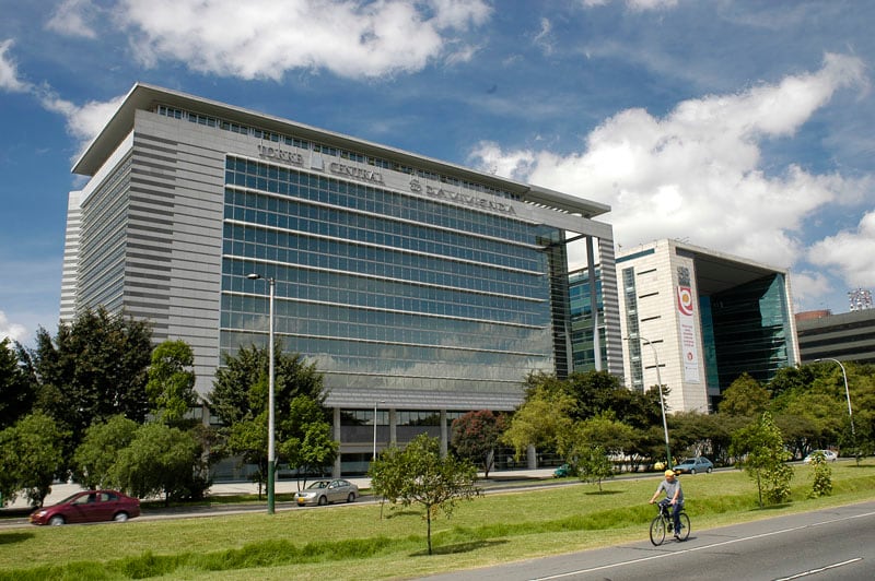 Edificio moderno de la Torre Central Davivienda en Bogotá, rodeado de zonas verdes, árboles y un ciclista transitando frente a la estructura.