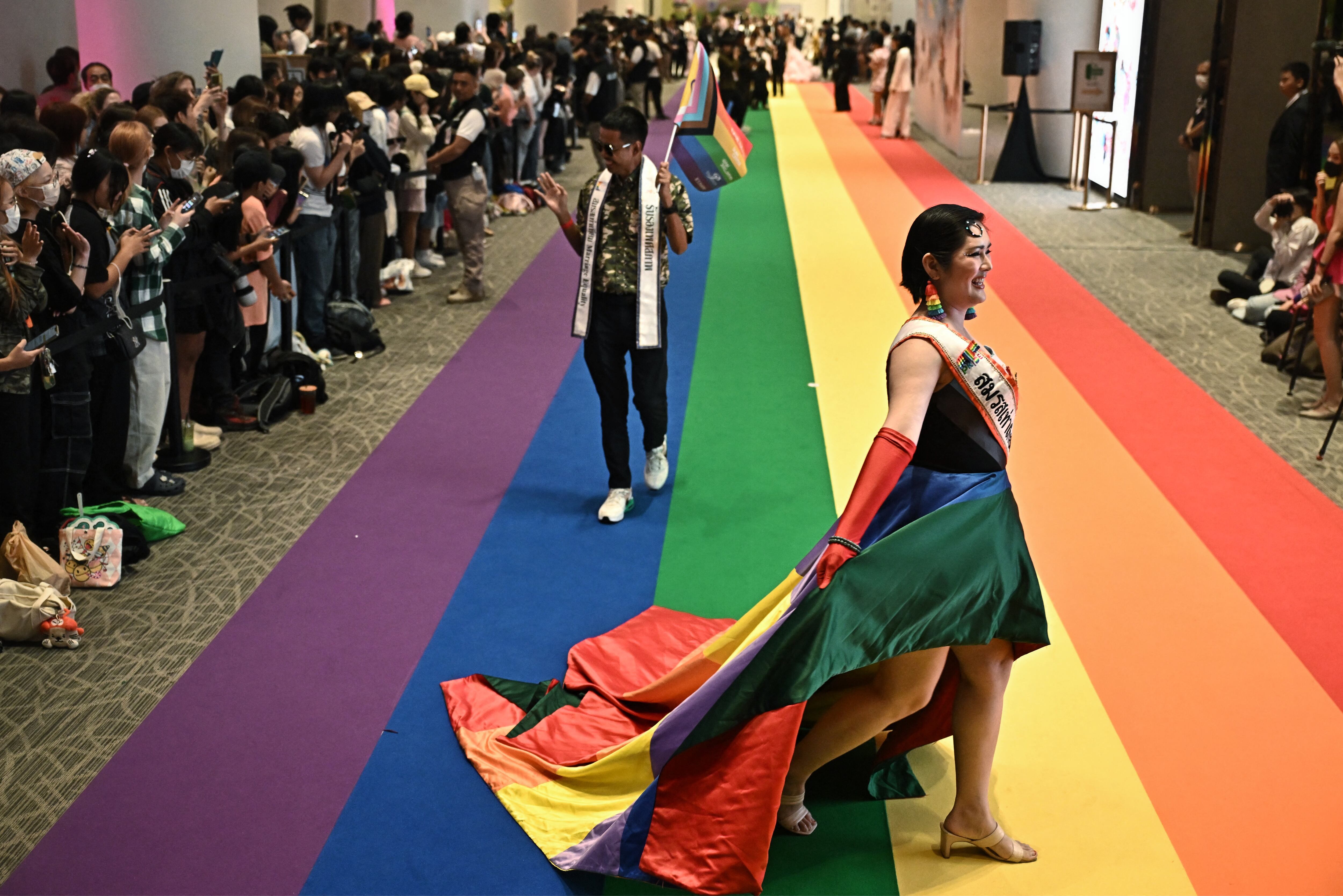 Miembros de la comunidad LGBTQ desfilan sobre una alfombra arcoíris durante un evento de registro matrimonial en el centro comercial Paragon de Bangkok, el 23 de enero de 2025.