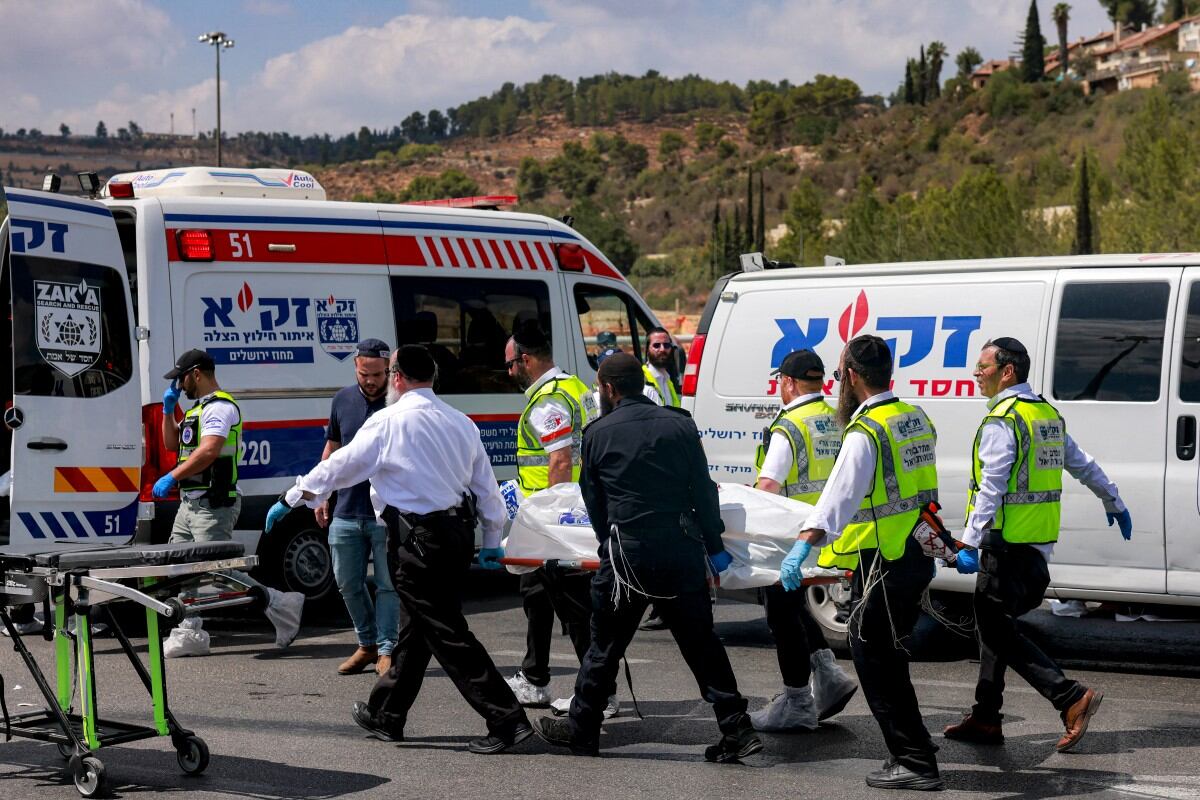 Cuerpos de socorro llevan cuerpo de un hombre cerca de la ambulancia.