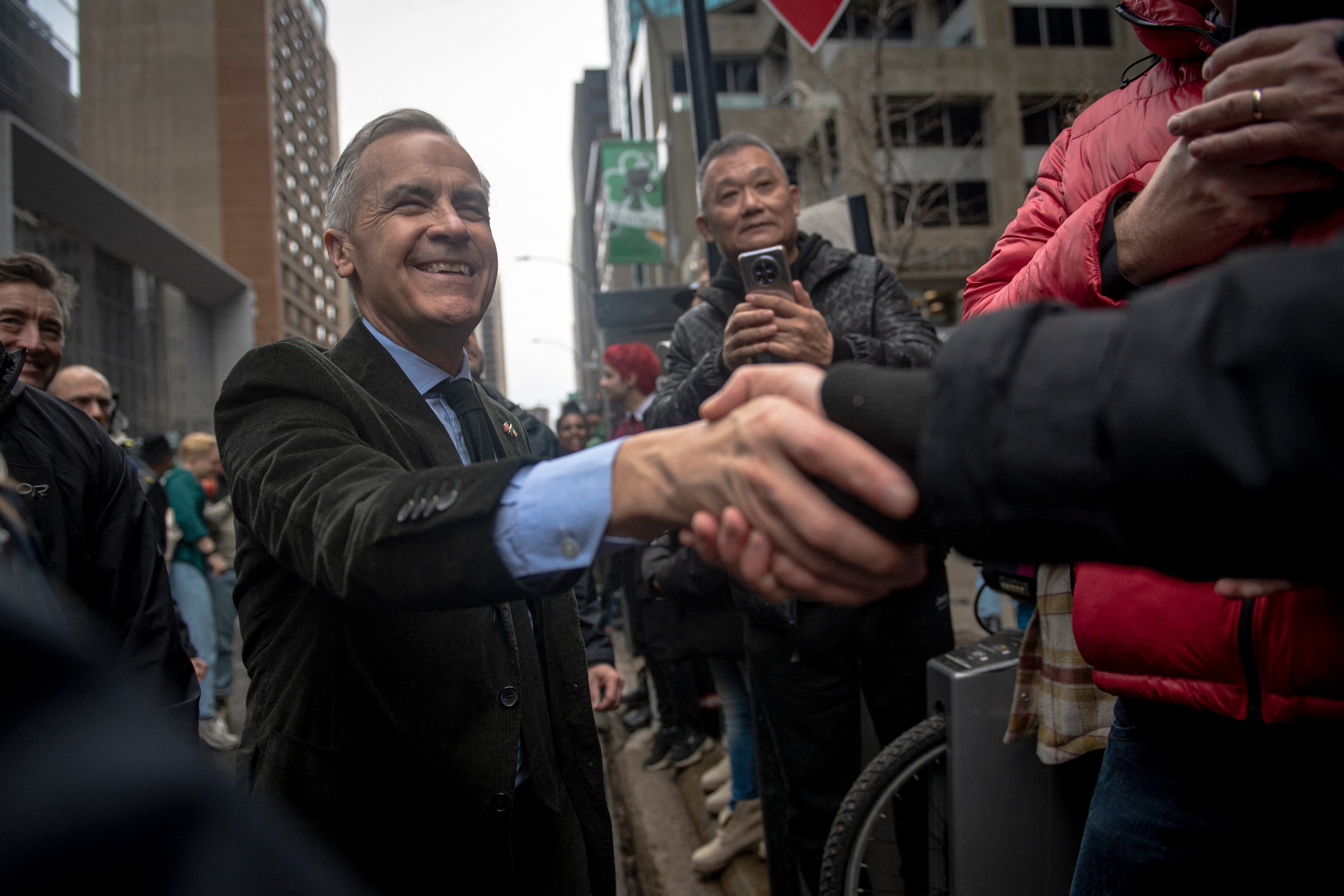 El primer ministro canadiense, Mark Carney (C), saluda a sus seguidores mientras participa en el desfile del Día de San Patricio en Montreal, Canadá, el 16 de marzo de 2025. El desfile de Montreal, el más antiguo de Canadá, celebra su 200.º aniversario. (Foto de ANDREJ IVANOV / AFP)