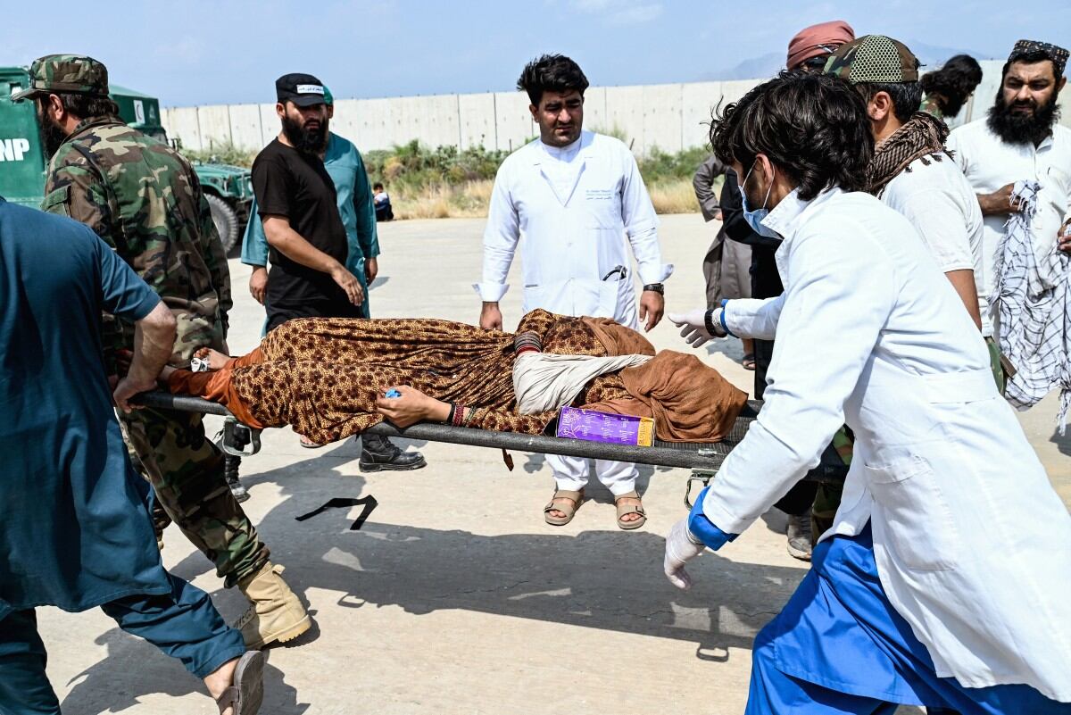 Taliban security personnel carry an earthquake victim evacuated by a military helicopter from the Nurgal district of Kunar province, after her arrival for medical assistance in Jalalabad on September 1, 2025.
