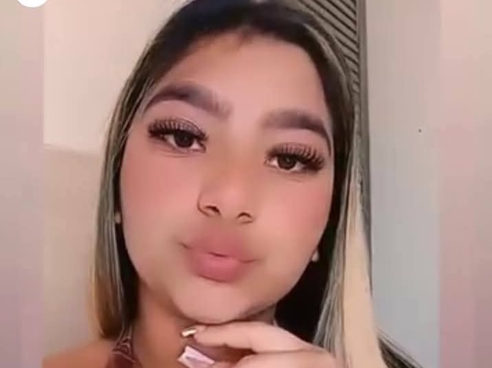 Se observa a una joven que mira a la cámara y parece lanzar un beso