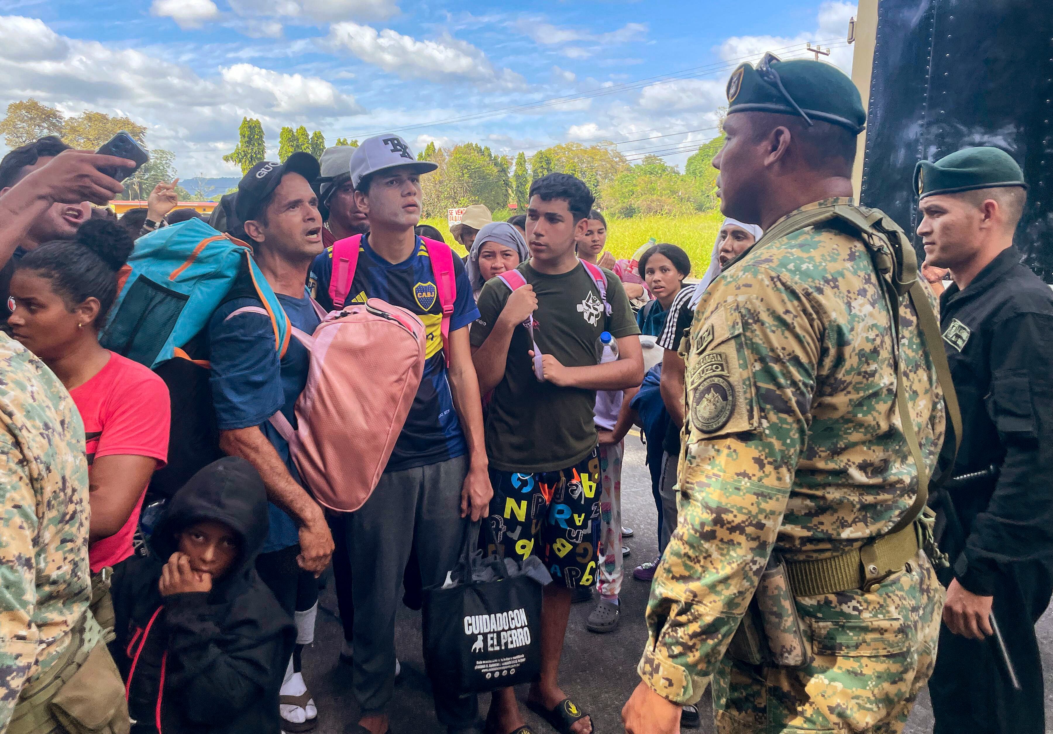Migrants talk to Panamanian National Border Service members as they try to cross the border between Panama and Costa Rica while trying to return to Venezuela, at Paso Canoas between Panama and Costa Rica border on February 11, 2025. Dozens of Venezuelan migrants crossed the border from Costa Rica into Panama on Tuesday in a small caravan as they gave up the journey to the United States, overwhelmed by the grueling journey and fearful of Donald Trump's harsh anti-immigrant policies. (Photo by PAUL MONTENEGRO / AFP)