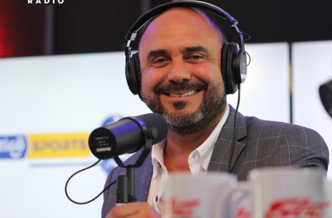 Primer plano de Kristian Mora con audífonos y tomando un micrófono