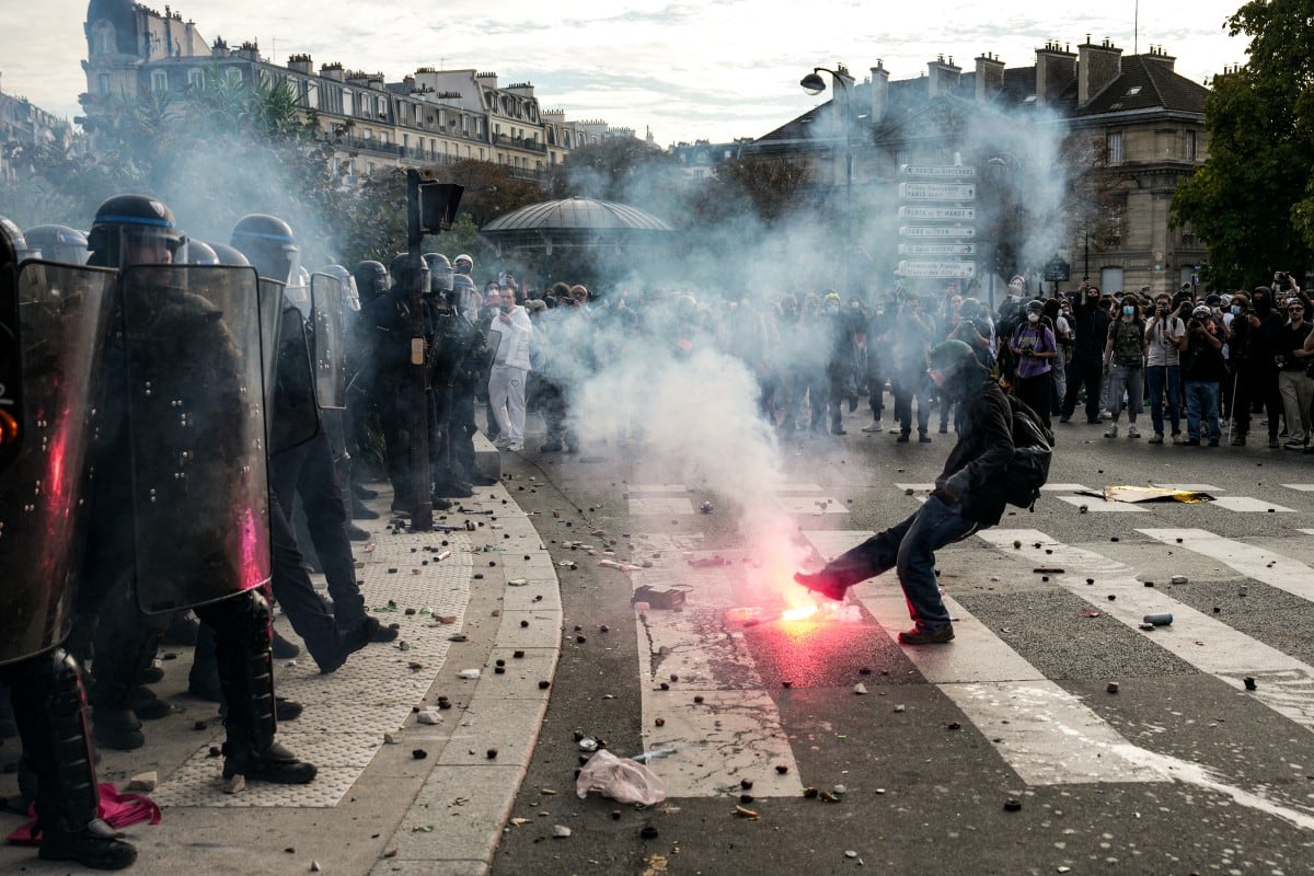 Una persona patea una bengala contra agentes de policía que dispersaban a manifestantes al término de una protesta, parte de una jornada nacional de movilizaciones convocada por estudiantes de secundaria y a la que se sumaron sindicatos y docentes en Francia.