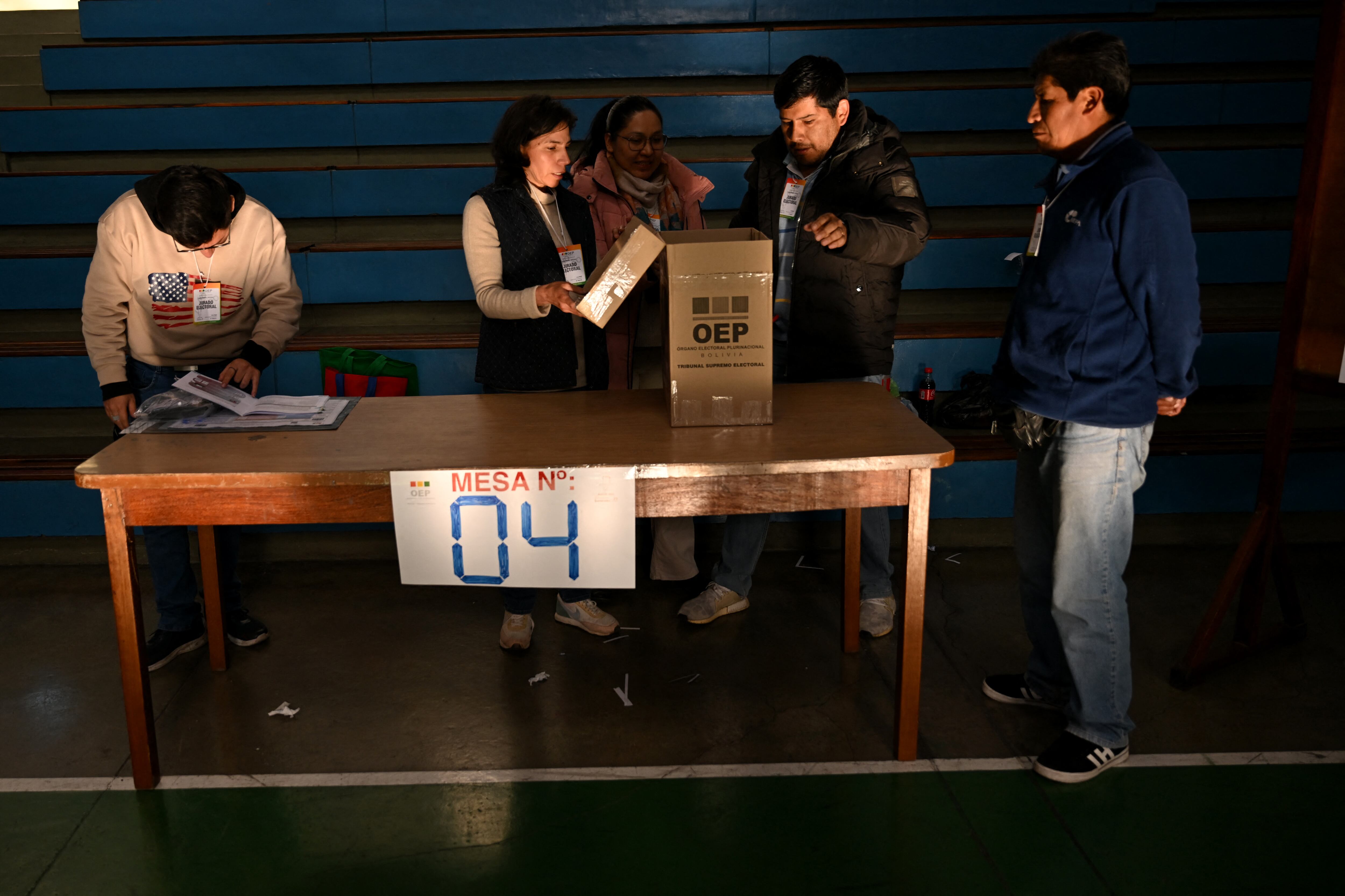 Una urna electoral y los jefes de mesa abriéndola.