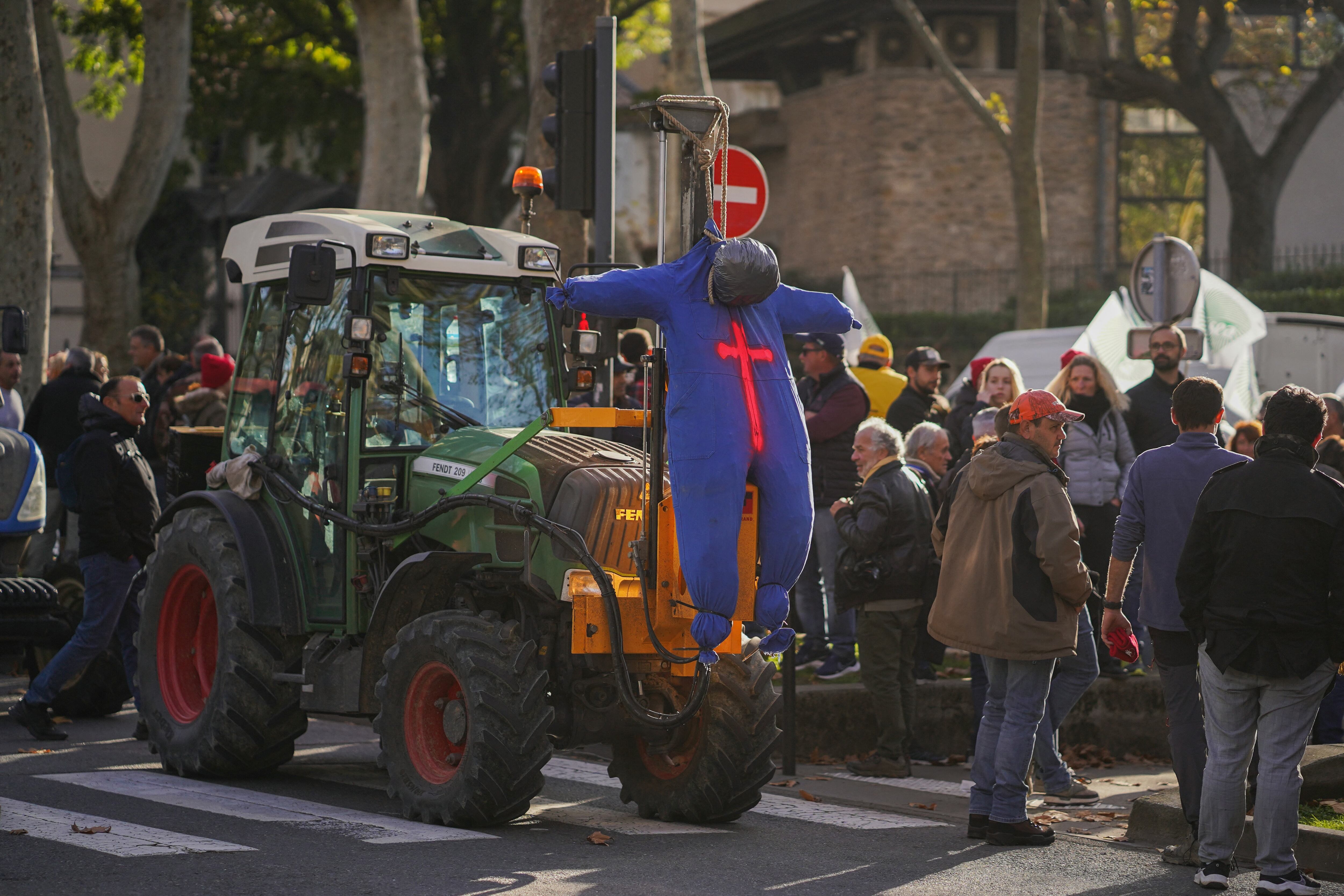 Agricultores franceses protestan con un muñeco colgado frente a un tractor, expresando su descontento contra las restricciones administrativas y políticas agrícolas en el centro de Francia.