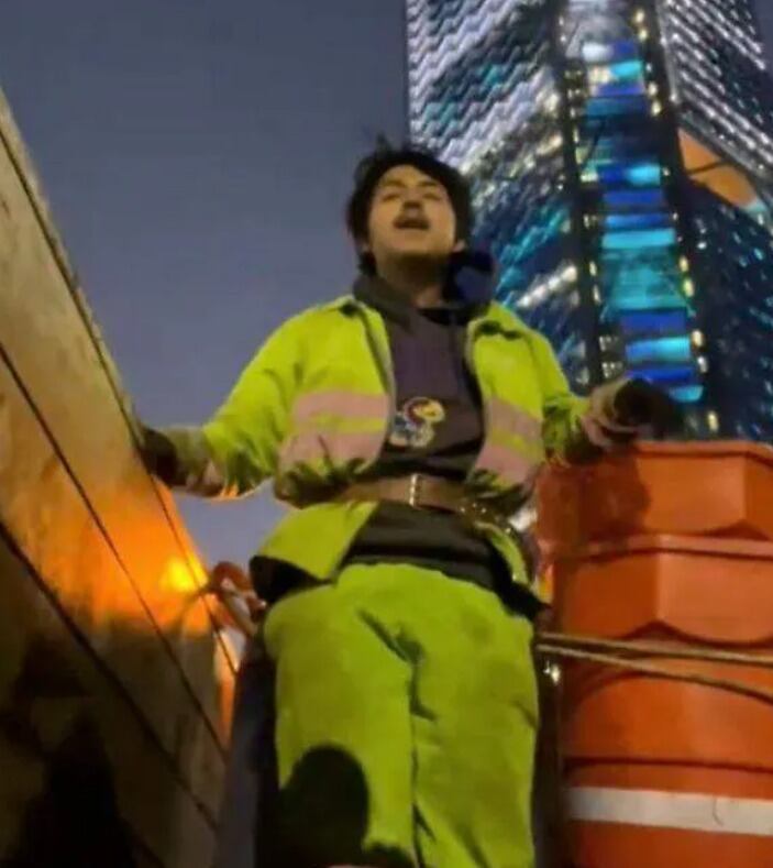 Foto de un joven barrendero subido en el camión de limpieza.