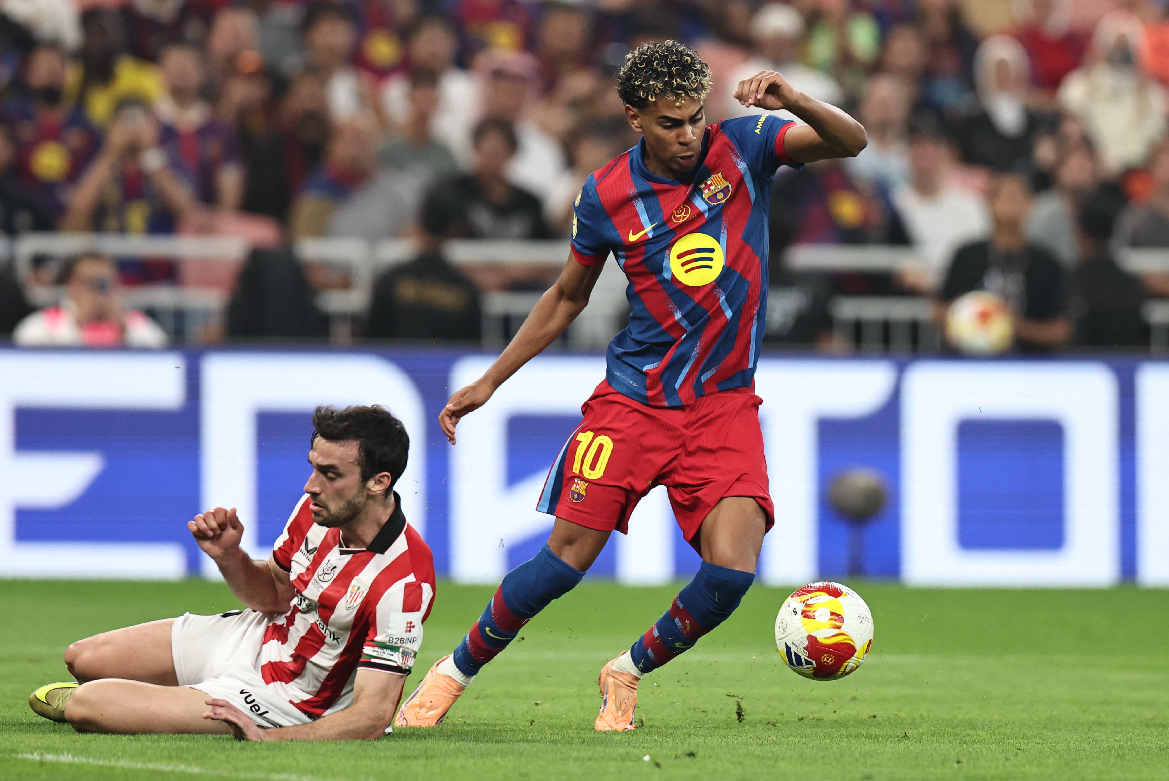 El delantero del Barcelona Lamine Yamal deja en el suelo al defensor Íñigo Lekue del Athletic Bilbao, durante la semifinal de la Supercopa de España en Arabia Saudita.