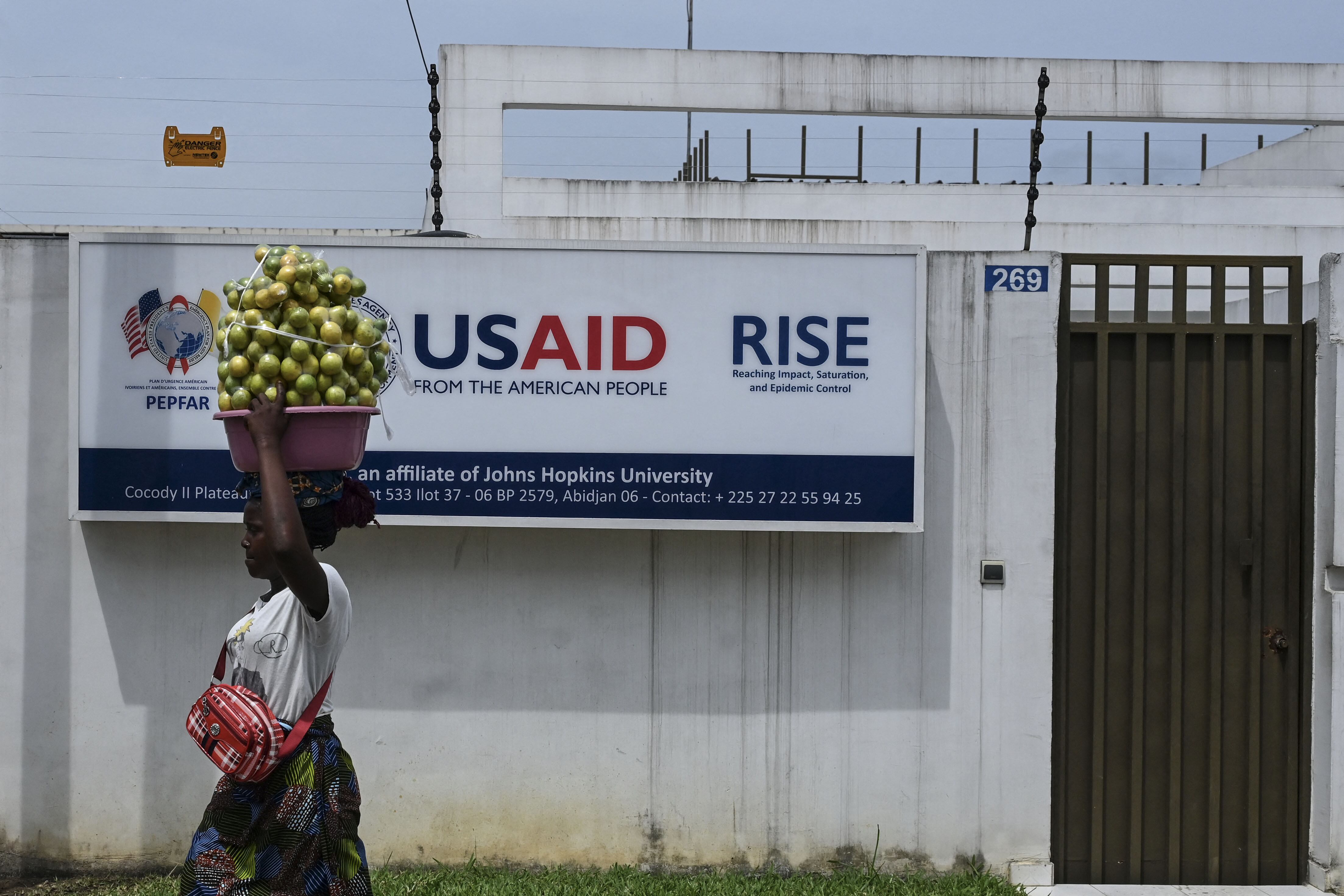 A Street vendor walks past the United States Agency for International Development (USAID) office in Abidjan on March 22, 2025. (Photo by Issouf SANOGO / AFP)