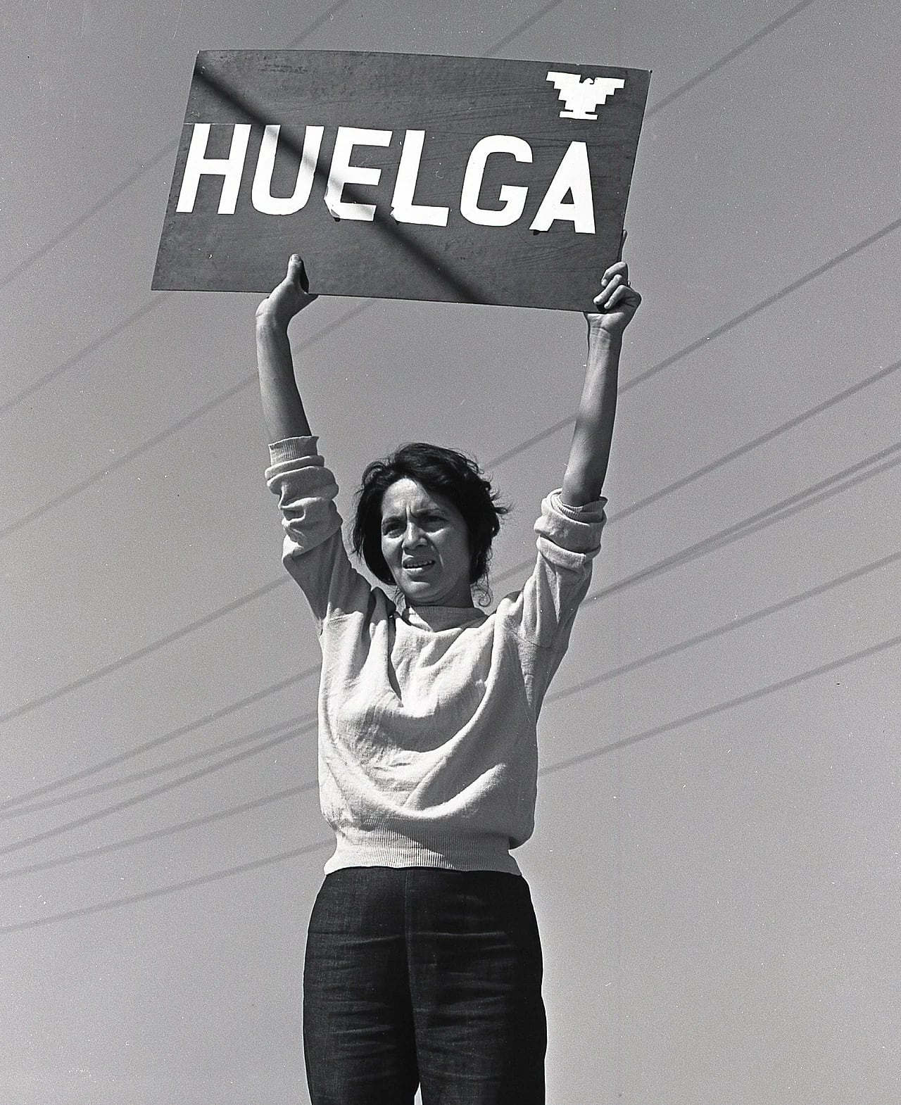 Dolores Huerta sostiene un cartel de El Malcriado, n.º 21, con la palabra «Huelga».