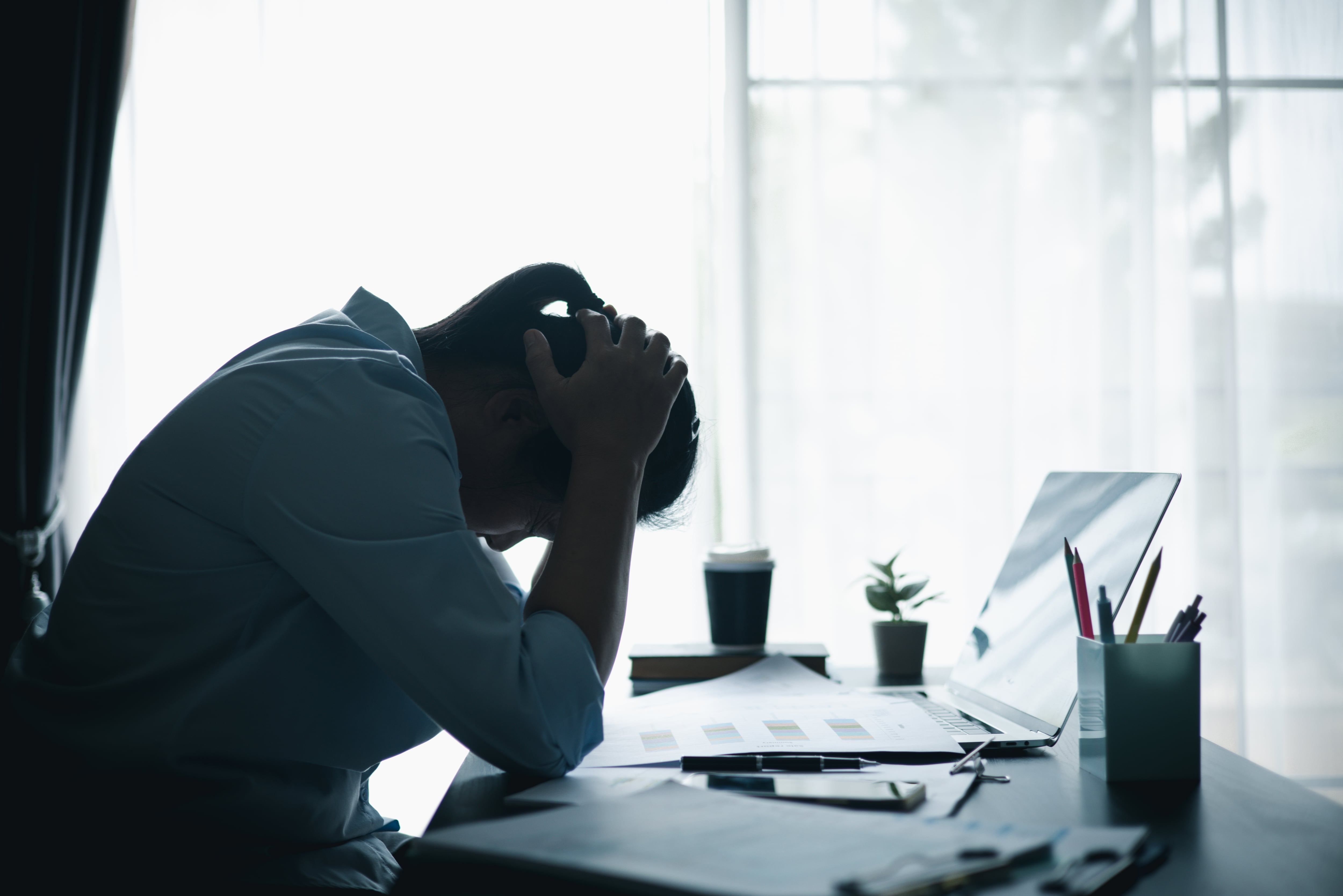 Burnout. Agotamiento. Mujer estresada trabajando hasta tarde en la oficina, sintiéndose agotada mientras revisa la computadora portátil. Concepto de estrés laboral y exceso de trabajo.