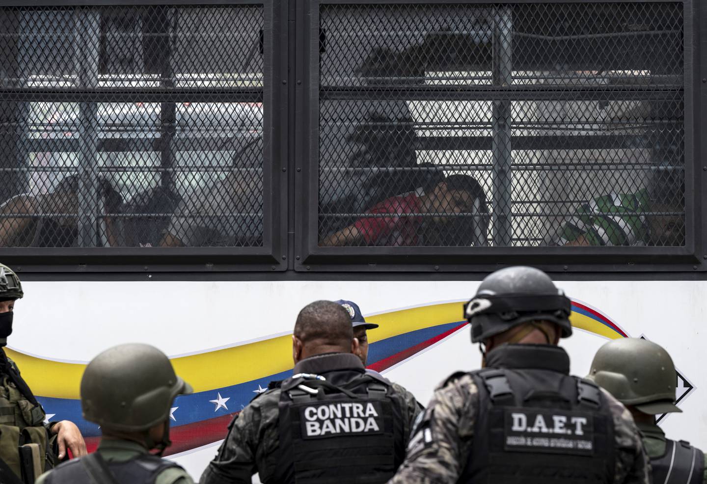 Miembros de la Guardia Nacional Bolivariana (GNB) hacen guardia mientras los reclusos a bordo de un autobús son trasladados fuera de la prisión de Tocorón