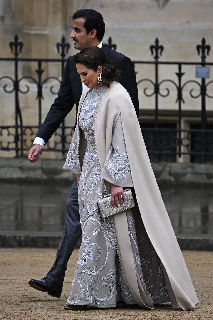 Noora bint Hathal Al Dosari, esposa del emir de Qatar, lució un vestido color gris, que con sus bordados resalta su cultura. Una larga capa formó parte del atuendo, que combinó con una elegante cartera a juego. 
