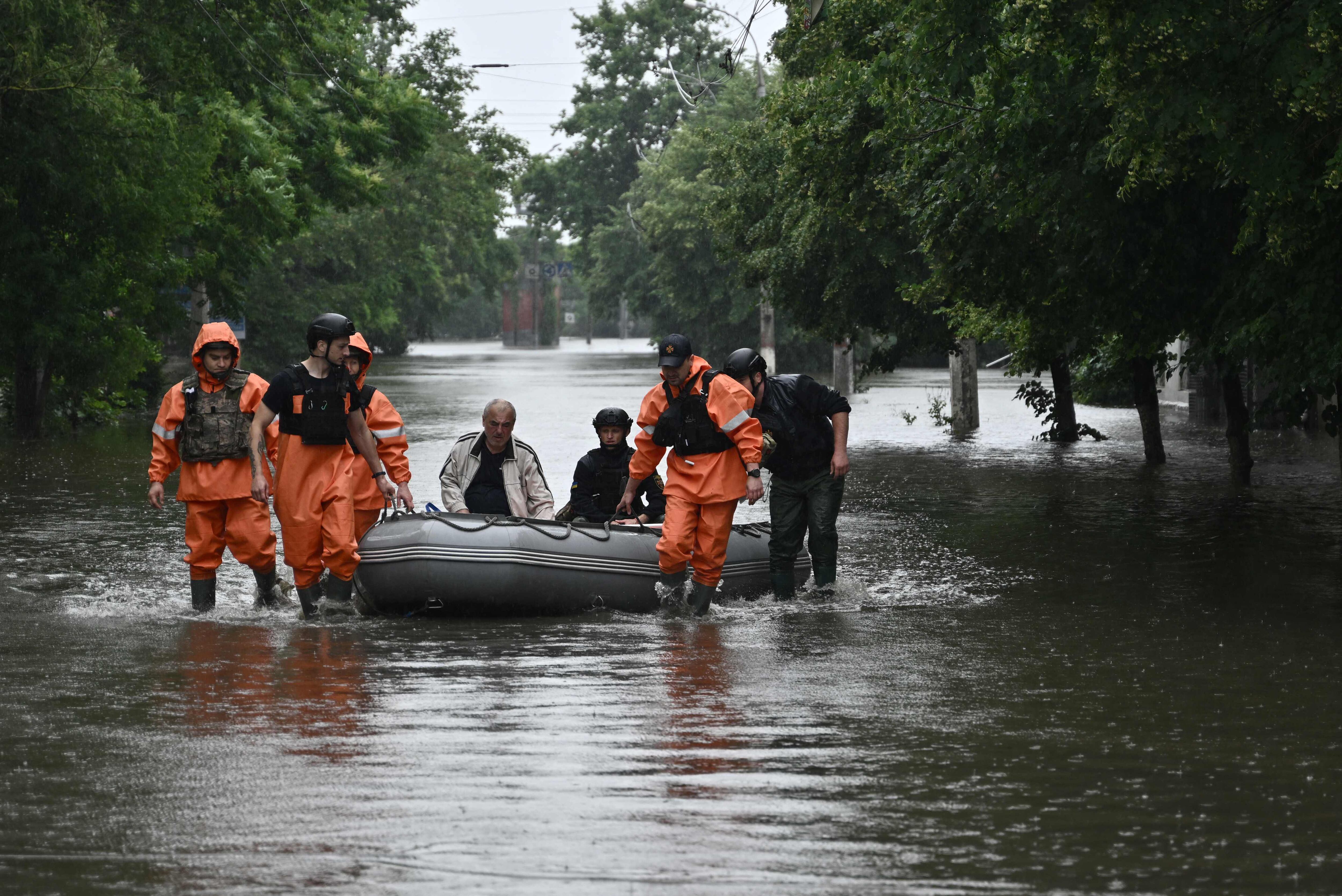 Rescatistas del Servicio Estatal de Emergencias ayudan a evacuar a un residente local de un área inundada en la ciudad de Kherson el 11 de junio de 2023. (Foto de Genya Savilov / AFP)