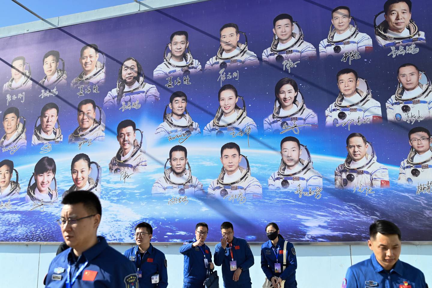 Las personas pasan frente a un cartel que muestra a los astronautas en el Centro de Lanzamiento de Satélites de Jiuquan en la provincia de Gansu, al noroeste de China